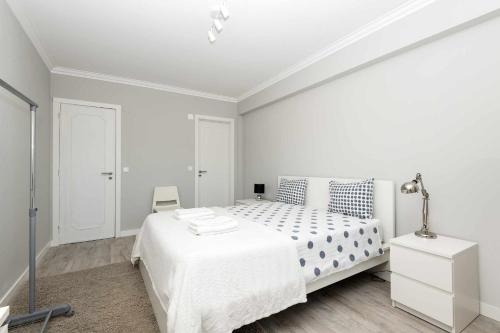 una camera da letto bianca con un letto bianco e una lampada di Cozy Apartment With Sea View in Estoril a Estoril