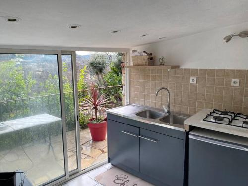 Il comprend une cuisine avec un évier et offre une vue sur une terrasse. dans l'établissement Charmante maison avec piscine, à Gourdon