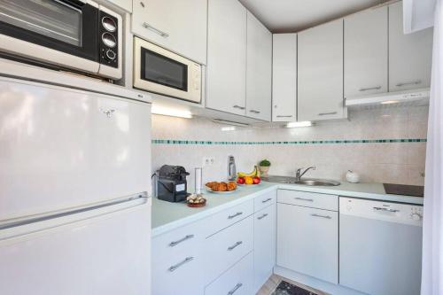 une cuisine blanche avec des armoires blanches et un micro-ondes dans l'établissement Forville - AzuRenting Conciergerie -centre ville, à Cannes
