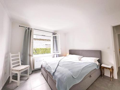 1 dormitorio con cama, ventana y silla en Casa Via Saleggi 10, en Ascona