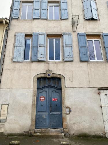 un edificio con una puerta y ventanas azules en Chez Mélissa 1, en Millau