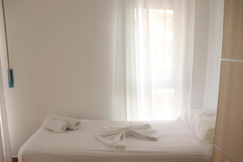 una cama blanca con una proa delante de una ventana en Panorama, en Vlorë