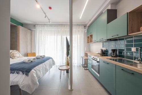 a bedroom with a bed and a kitchen with blue cabinets at Stylish Urban Suites in Athens