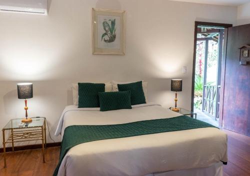 a bedroom with a large white bed with green pillows at Kastel Pedra Bonita in Petrópolis