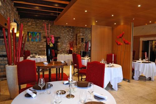 un restaurant avec des tables blanches, des chaises rouges et un chercheur de table dans l'établissement La Chaumiere, à Dole