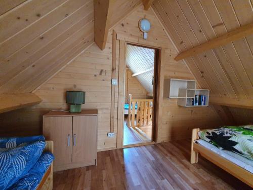 a log cabin with a bed and a door to a room at Hals domki letniskowe in Ustronie Morskie