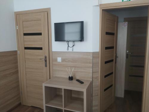 a room with a tv on the wall and a table at Pokoje Gościnne z łazienkami przy Wrocławiu, darmowy parking in Długołęka