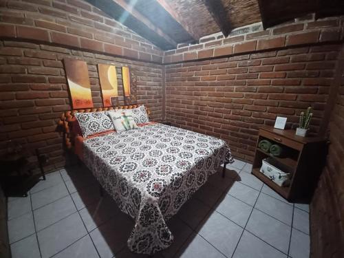 um quarto com uma cama e uma parede de tijolos em CABAÑA LA GRULLA em Santa Verónica