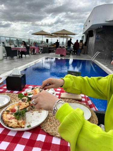 a person sitting at a table with a plate of pizza at Sky Roof Hotel in North Nicosia