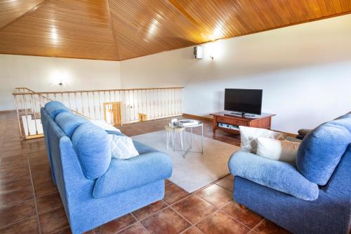 a living room with two blue chairs and a television at A Casa de Lamas in Meis