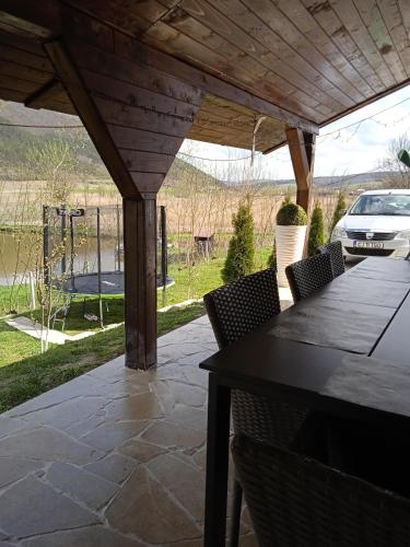 eine Terrasse mit Tisch und Stühlen und ein Auto im Hintergrund in der Unterkunft Vila Sabo- Casa de vacanta cu lac de pescuit si ciubar cu hidromasaj in Sîntioana