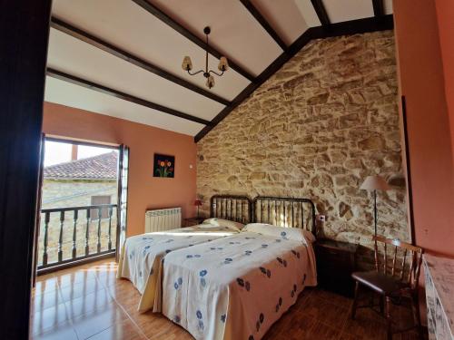a bedroom with a bed and a stone wall at Turismo rural El Piensu in Villaviciosa