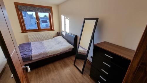 Dormitorio pequeño con cama y espejo en Self-catering extended family home en Edimburgo