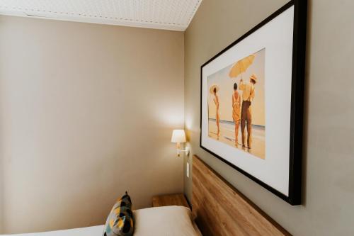 a bedroom with a picture of people on the beach at Hôtel Le Petit Castel in Antibes