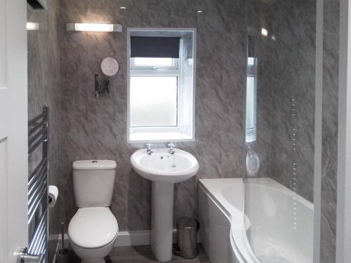 een badkamer met een toilet, een wastafel en een bad bij Quay Side in Cemaes Bay