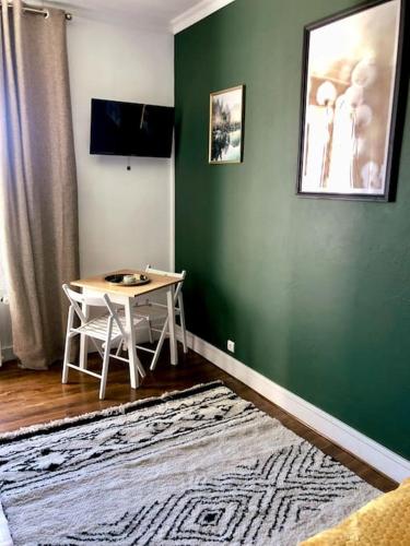 Cette chambre comprend une table et un mur vert. dans l'établissement Appartement Cosy proche Futuroscope, à Jaunay-Clan