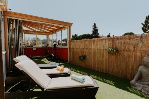 a patio with two lounge chairs and a fence at Hôtel Le Petit Castel in Antibes