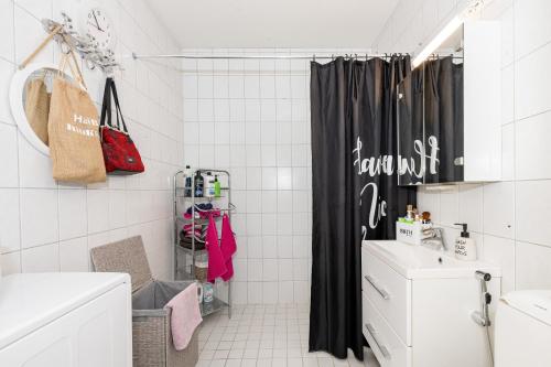 un bagno bianco con tenda da doccia nera di Casa Merikotilo merellisessä Meriraumassa. a Rauma
