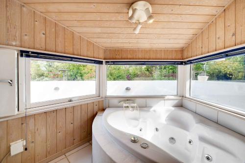 bañera en una habitación con 2 ventanas en Holiday Home With Big Terrace And Panoramic View To Nature en Tikøb