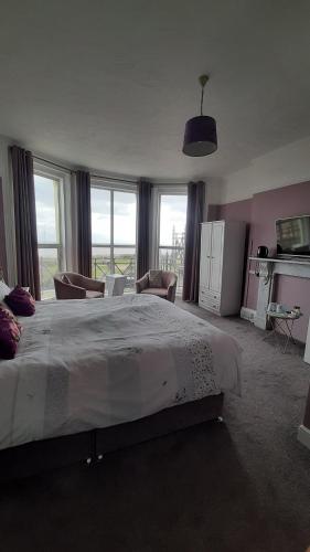 una grande camera da letto con un grande letto e finestre di The Coventry Guest House a Lowestoft