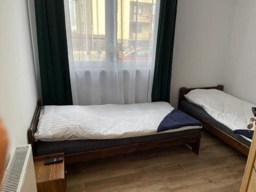 two beds in a room with a window at Irys 1 in Tychy
