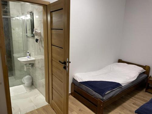 a bedroom with a bed and a shower and a sink at Irys 1 in Tychy