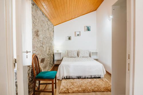 a bedroom with a bed and a chair at Forno House - A Cabana in Vila Praia de Âncora