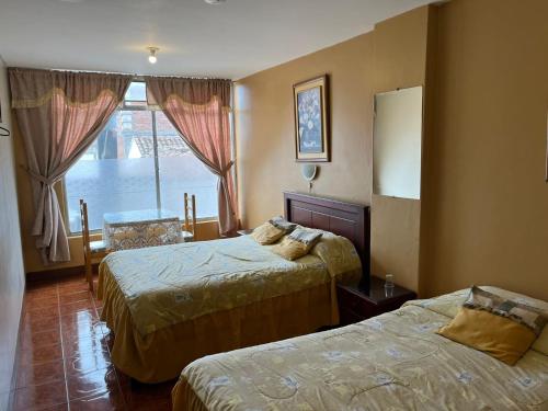 a hotel room with two beds and a window at Hotel Cotopaxi in Latacunga