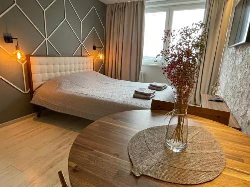 a bedroom with a bed and a table with a vase on it at Central place with lake view in Šiauliai