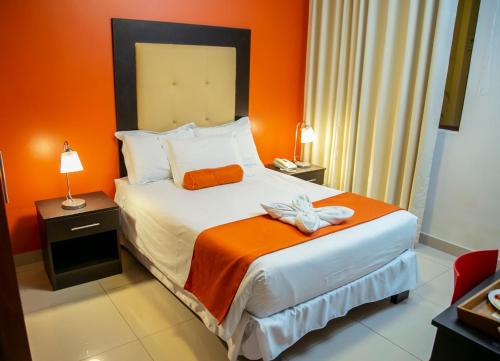 1 dormitorio con 1 cama con pared de color naranja en Hotel Killari Trujillo, en Trujillo