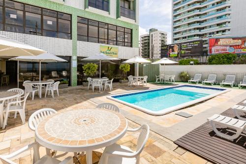 a patio with tables and chairs and a swimming pool at Yak Beach Hotel Ponta Negra in Natal