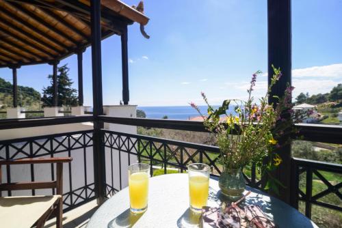 a table with two glasses of orange juice on a balcony at Irida Apartments in Stafylos