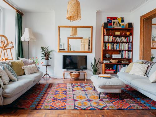 a living room with two couches and a tv at Enchanted Rose Garden House in Falmouth