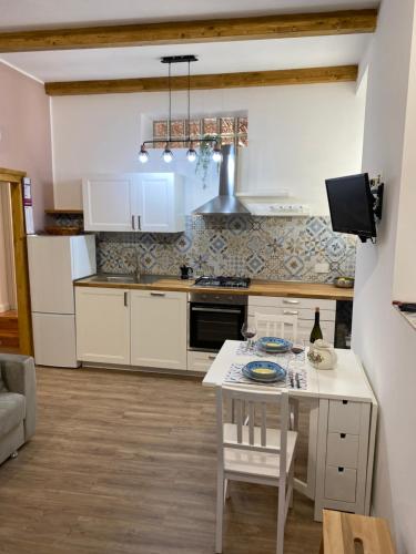 ZagaroloにあるCasa di Milaのキッチン(白いキャビネット、テーブル、椅子付)