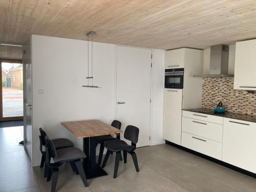 a kitchen with white cabinets and a wooden table and chairs at Lin et l'autre appartement in Limmen