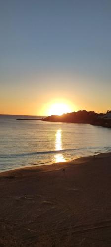 a sunset on a beach with the sun setting at AlbufeiraSun, arrive as a guest leave as a friend. in Albufeira
