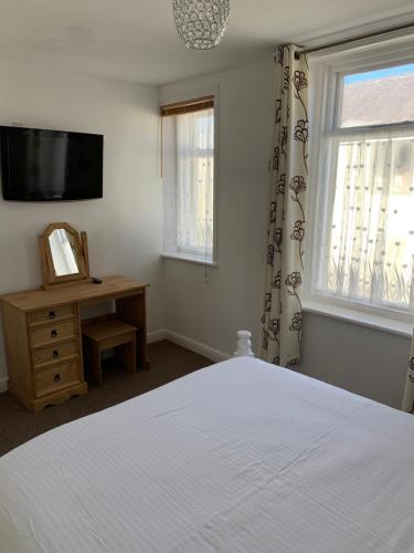 a bedroom with a bed and a television and a window at Delamere holiday flat in Blackpool