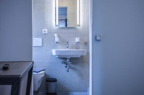 a bathroom with a sink and a toilet and a mirror at Hotel Pame Grill in Eching