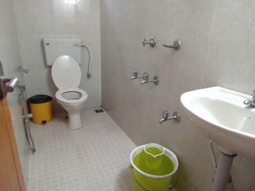 a bathroom with a toilet and a sink and a trash can at ChristVille in Cochin