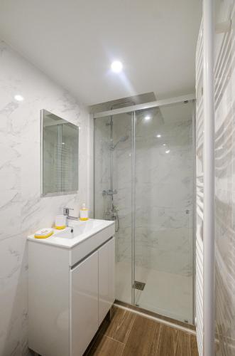 une salle de bain blanche avec un lavabo et une douche dans l'établissement Villa Forestière Studio l'Olivier, à Quincy-Voisins