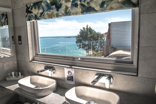 a bathroom with two sinks and a large window at The Pines Hotel in Swanage