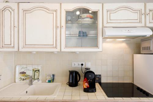 une cuisine avec des armoires blanches et un évier dans l'établissement Magnolia YourHostHelper, à Sainte-Maxime