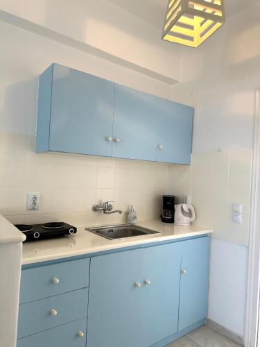 a kitchen with blue cabinets and a sink at Kleanthi Apartments in Drios