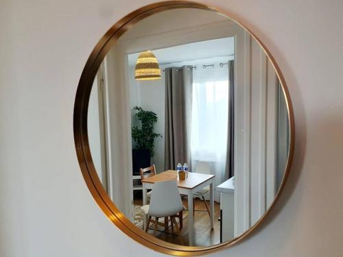 a mirror hanging on a wall with a table and chairs at Le Cosy Palm Tree by Madame Conciergerie in Bruz