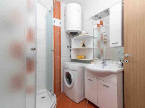 a bathroom with a washing machine and a sink at Cozy House in Seget Vranjica