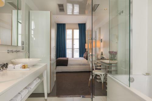 a bathroom with a tub and a sink and a bedroom at Hotel Le Placide Saint-Germain Des Prés in Paris