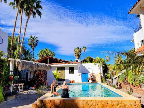two women sitting on the edge of a pool in front of a house at Villas del Santo Niño in Loreto