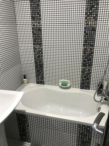 a white bath tub in a bathroom with black tiles at JP Apartment in Dubai