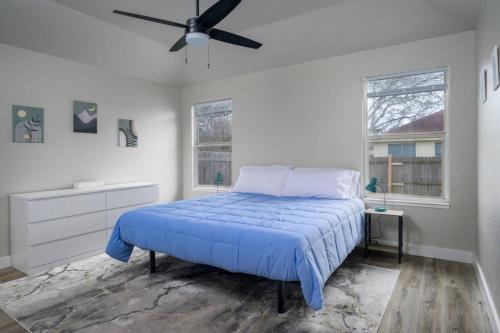 1 dormitorio con 1 cama azul y ventilador de techo en Palagi Place, en Austin