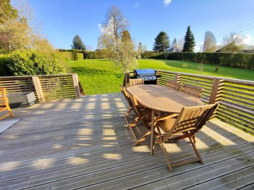 une table et des chaises en bois sur une terrasse en bois dans l'établissement Les Délices de la Vie, à Le Mesnil-Germain